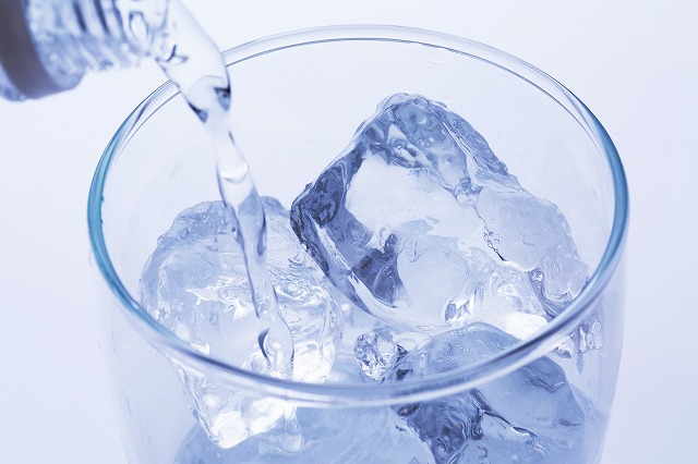 氷が入ったグラスに飲み物を注ぐ