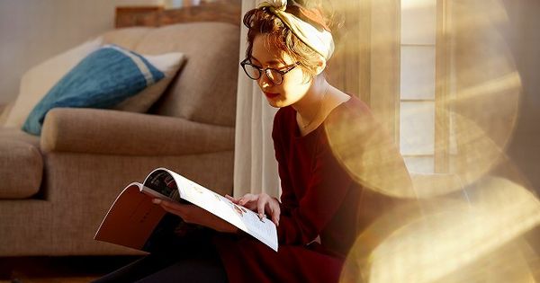 一人暮らしのの部屋で読書をする女性の画像