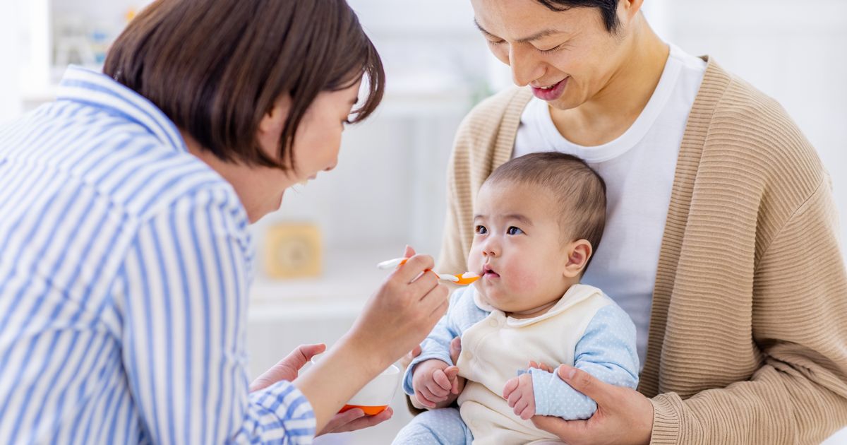 家族で赤ちゃんにベビーフードを食べさせる画像