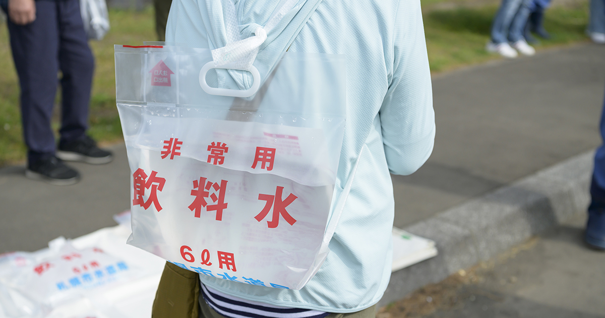 非常用飲料水を背負う女性